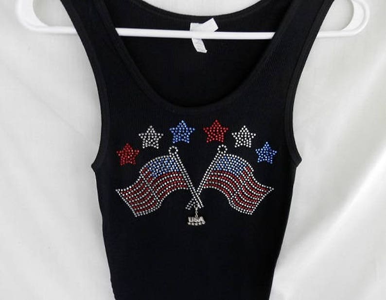 May include: Black tank top with a rhinestone design of two American flags and stars.
