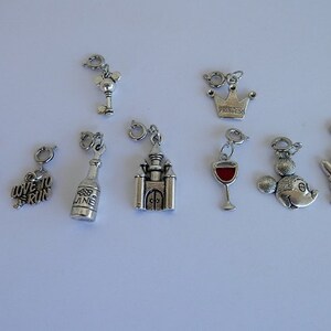 May include: A set of ten silver charm pendants, including a wine bottle, a running shoe, a castle, a wine glass, a key, a crown with the word "Princess" on it, and two Mickey Mouse heads.