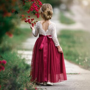 Burgundy long sleeve flower girl dress made of lace and tulle, designed for toddlers, girls, and junior bridesmaids attending fall or winter weddings.