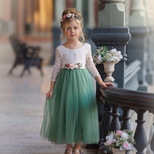 Long sleeve lace and tulle flower girl dress available in sage green, dusty blue, blush, ivory, burgundy, and more, perfect for all wedding themes.