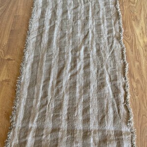 Puede incluir: Un camino de mesa de lino a rayas beige y blanco con bordes deshilachados.