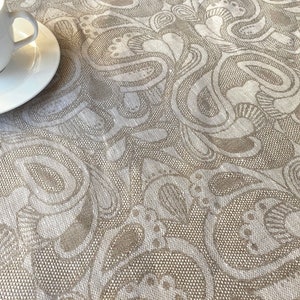 Könnte beinhalten: Eine weiße Tischdecke mit einem beigefarbenen Paisley-Muster. Die Tischdecke hat eine subtile Textur und ein zartes Design.