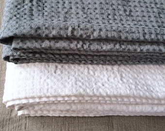 May include: A stack of two waffle weave towels, one gray and one white. The towels are folded and have a textured surface.