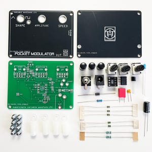 May include: An assortment of electronic components for a pocket modulator project, including black panels with text, a green circuit board, knobs, and various small parts. The text on the black panel reads "VARIABLE WAVESHAPE LFO" and "POCKET MODULATOR OUT".