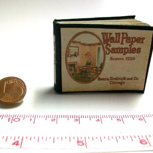 May include: A small, black-bound book with a cream-coloured cover. The cover features a vintage illustration of a room interior and the text "Wall Paper Samples Season 1920 Sears, Roebuck and Co. Chicago."