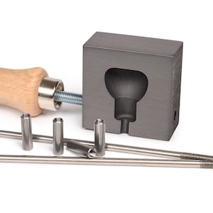Op de afbeelding: Een grijze metalen mal voor het gieten van een gloeilampvorm, met een houten handvat en metalen staven.