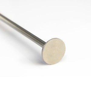 Op de afbeelding: Een zilveren metalen staaf met een ronde, platte kop. De staaf is glad en glanzend.