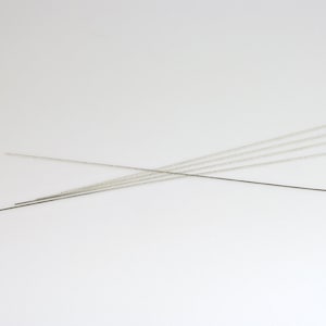 Puede incluir: Un juego de seis varillas de soldadura de metal de color plateado.