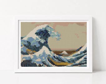 May include: A cross-stitch embroidery of a large ocean wave in shades of blue, white, and yellow, set against a beige background. The artwork is displayed within a simple white rectangular frame, showcasing a detailed grid-like needlework pattern.
