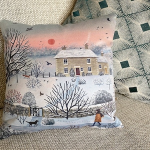 Faux suede cushion of a winter scene with a cottage and dog walker, printed from an original painting 'Nearly Home' by Jo Grundy