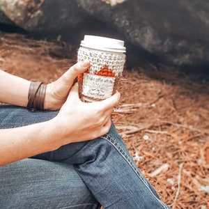 May include: A white crocheted coffee cup cozy with a brown label that reads "I'll take coffee with you Sunshine".