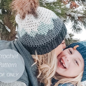 May include: A close-up of two people wearing crocheted hats. The person in the front is smiling and wearing a blue and white hat. The person in the back is wearing a gray, white, and blue hat with a brown pom-pom. The text "Crochet Pattern PDF ONLY" is visible in the image.
