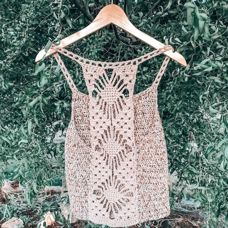 May include: A crocheted tank top with a delicate openwork design at the back. The top is made with a beige yarn with brown and white flecks.
