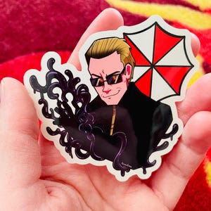 May include: A sticker featuring a stylized illustration of a man in sunglasses, with a black jacket and a red and white umbrella logo. The sticker has a black, swirling design on the left side.