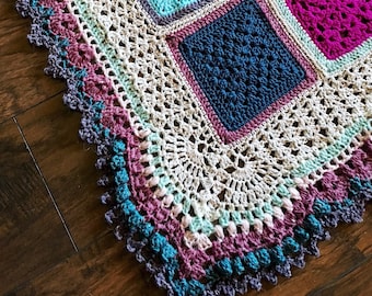 May include: A crocheted blanket with a multi-colored border and a variety of square patterns in shades of blue, teal, pink, and purple.
