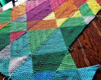 May include: A colorful knitted blanket with a geometric pattern in shades of blue, green, red, orange, yellow, and purple.