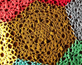 May include: A crocheted blanket made of different colored squares. The squares are in shades of yellow, green, red, and brown.