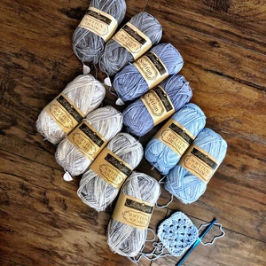 May include: A collection of ten skeins of yarn in various shades of blue and white. The yarn is labeled "Scheepjes Soft Fun" and comes in the colors "Denim" and "Aquarel". A crocheted square is also included in the image.