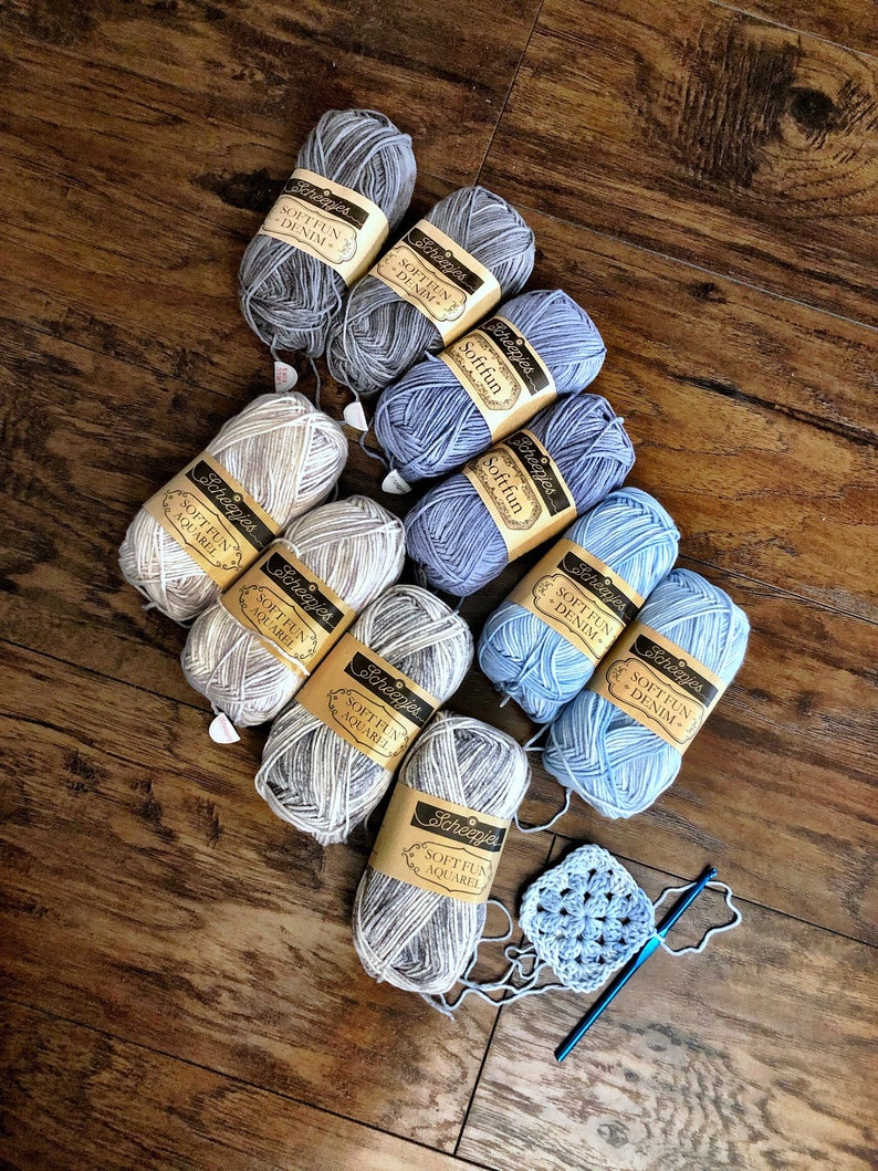 May include: A collection of ten skeins of yarn in various shades of blue and white. The yarn is labeled "Scheepjes Soft Fun" and comes in the colors "Denim" and "Aquarel". A crocheted square is also included in the image.