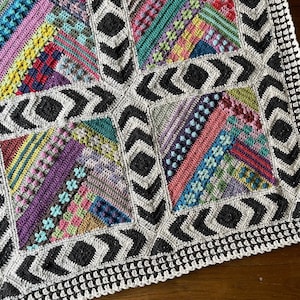 Op de afbeelding: Een kleurrijk gehaakt deken met een geometrisch patroon. Het deken is gemaakt met verschillende gekleurde garens en heeft een zwart-witte rand.