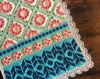 May include: A crocheted blanket with a green and pink floral pattern and a blue and green geometric pattern. The blanket has a white crocheted border.