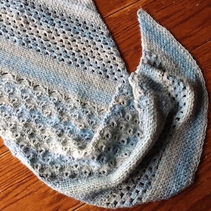 May include: A crocheted shawl in shades of blue and gray with a lacy pattern.