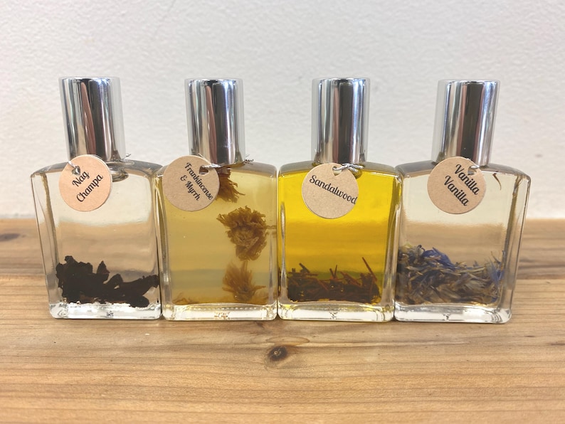 May include: Four small glass bottles with silver caps and brown paper labels. The labels have the names of different scents: Nag Champa, Frankincense & Myrrh, Sandalwood, and Vanilla Vanilla.