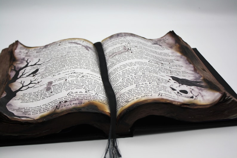 May include: An open, antique-looking book with brown leather binding and aged pages. The pages are filled with text and illustrations, including a skeletal skull and a raven. The book is open to a page with the text "Quoth the Raven, Nevermore".