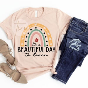 May include: A pink t-shirt with a rainbow design and the text "It's a beautiful day to learn".