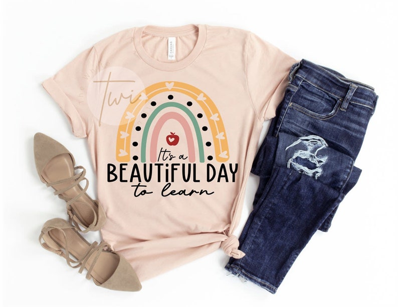 May include: A pink t-shirt with a rainbow design and the text "It's a beautiful day to learn".