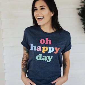 May include: A navy blue t-shirt with the text "oh happy day" printed in rainbow colours.
