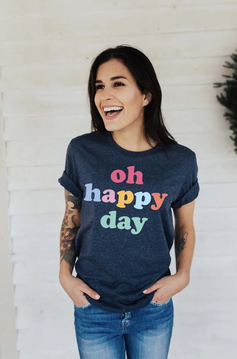 May include: A navy blue t-shirt with the text "oh happy day" printed in rainbow colours.