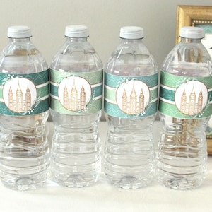 May include: Four clear plastic water bottles with green and gold labels featuring a temple design. The labels have the text "Stand ye in holy places".