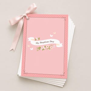 May include: A stack of pink baptism cards tied with a light pink satin ribbon. The cards feature a pink background with white polka dots, a decorative border, and the text "My Baptism Day" on a banner with floral accents and butterflies.