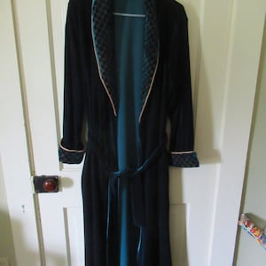 May include: A dark blue velvet robe with a teal lining and a patterned collar. The robe has a tie belt and long sleeves.