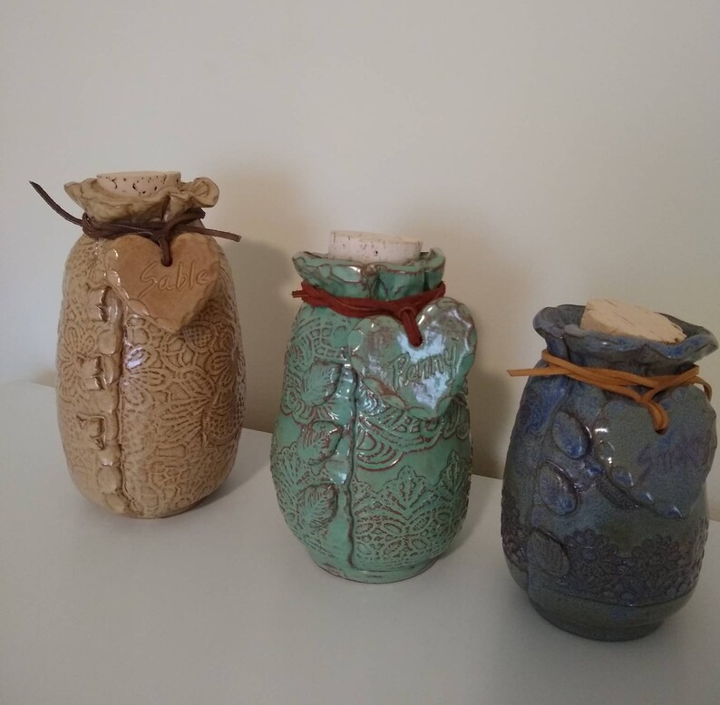 your choice of color and size. Ceramic Pet Urn is embossed with lace and personalized with a heart hung on a leather cord with pet/'s name