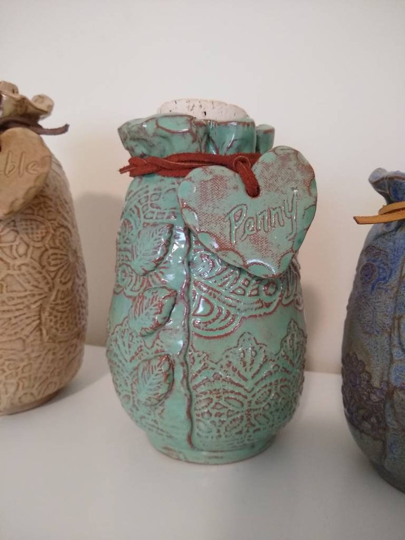 your choice of color and size. Ceramic Pet Urn is embossed with lace and personalized with a heart hung on a leather cord with pet/'s name