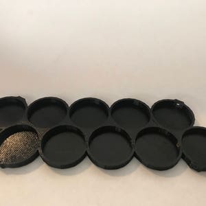 Peut inclure: Plateau de peinture en plastique noir avec dix d&eacute;pressions circulaires pour contenir des pots de peinture.