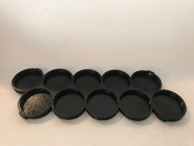 Peut inclure: Plateau de peinture en plastique noir avec dix d&eacute;pressions circulaires pour contenir des pots de peinture.