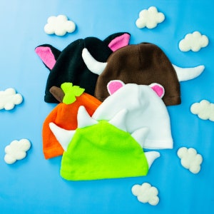 May include: Five colorful knitted hats with animal ears. The hats are made of soft, plush fabric and are perfect for keeping warm in the winter. The hats are in a variety of colors, including brown, black, white, green, and orange.