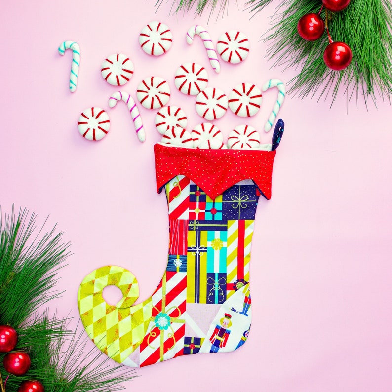 May include: A red and white Christmas stocking with a colourful patchwork design. The stocking is filled with white candy canes and peppermint sweets.