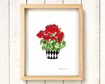 May include: A framed watercolor print of a potted geranium plant. The plant features vibrant red flowers and green leaves, set in a black and white diamond-patterned pot. The artwork is displayed in a light wood frame.