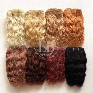 May include: Eight bundles of wavy hair extensions in various shades, including blonde, light brown, auburn, and black. Each bundle is secured with a thin, gold-colored band. The hair appears to be of high quality, with a natural wave pattern.