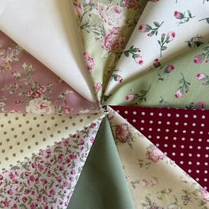 May include: A collection of fabric swatches arranged in a circular fan pattern. The textiles feature various designs including solid white, solid sage green, deep red with white polka dots, light green with polka dots, and floral prints in pink, green, and cream.