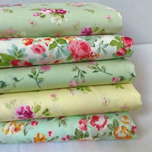 May include: A stack of five fabric squares with a floral pattern. The fabric is a light green colour with pink and yellow flowers.