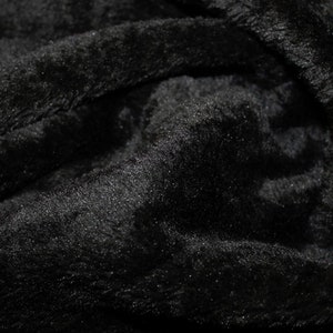 K&ouml;nnte beinhalten: Nahaufnahme eines schwarzen, flauschigen Stoffes mit weicher, pl&uuml;schiger Textur.