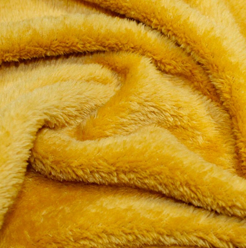 K&ouml;nnte beinhalten: Nahaufnahme eines weichen, gelben Kunstpelzes. Der Stoff hat eine flauschige Textur und eine warme, einladende Farbe.