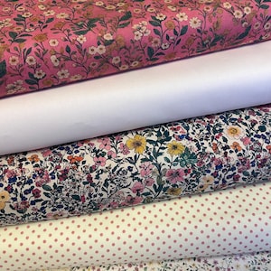 May include: Several fabric rolls with various patterns. The top roll has a pink floral design, followed by a plain white roll, then a roll with a colourful floral pattern, a pink polka dot roll, and a floral roll at the bottom.
