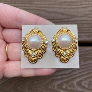 Joyas antiguas firmadas por Kenneth Jay Lane para Avon. Hermosos aretes con diamantes de imitación y perlas en tono dorado. Nuevos en caja