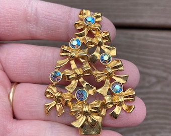May include: A gold-toned Christmas tree brooch with iridescent blue rhinestones and bows.